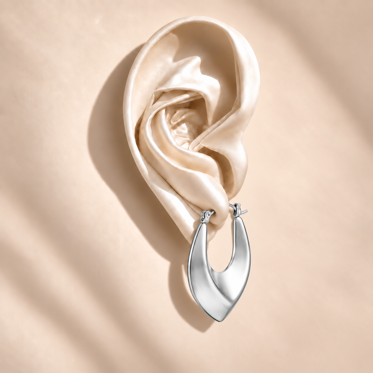 Vela Silver Sculptural Hoop on an ivory satin ear