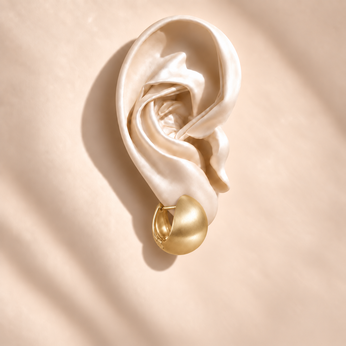 Luna Gold Dome earring at a side angle on an ivory satin ear