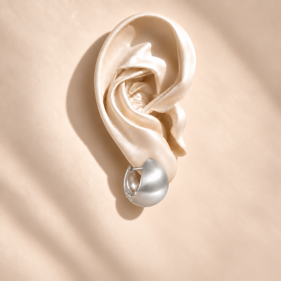 Luna Silver Dome earring at a side angle on an ivory satin ear