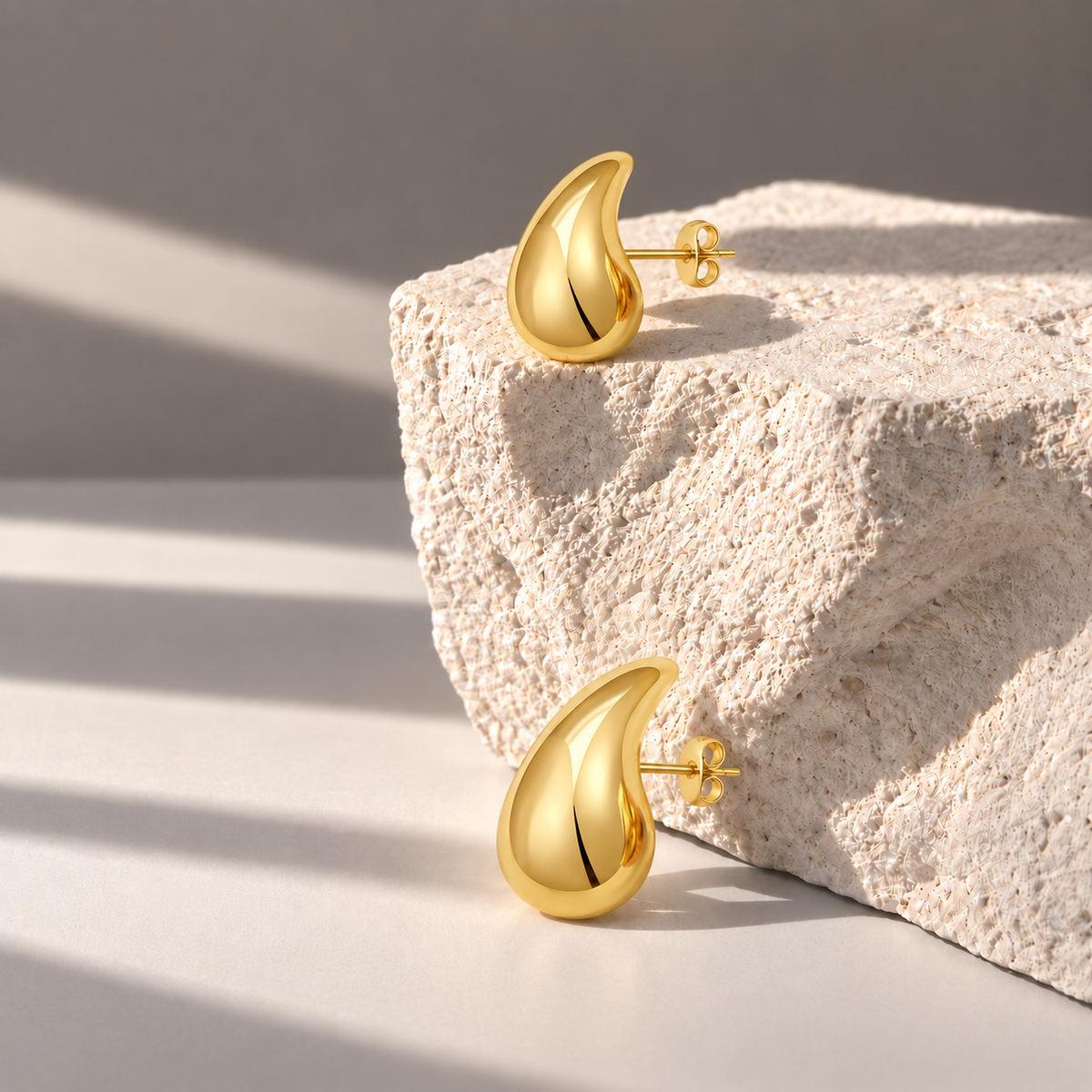 Solène Gold Teardrop Studs on pale limestone
