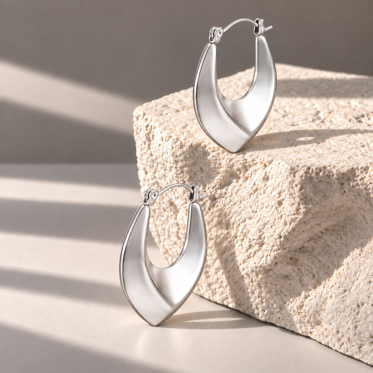 Vela Silver Sculptural Hoops on pale limestone