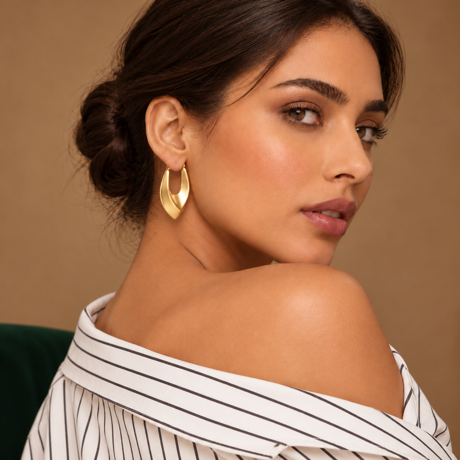 Vela Gold Sculptural Hoops worn by a model in an ivory striped shirt