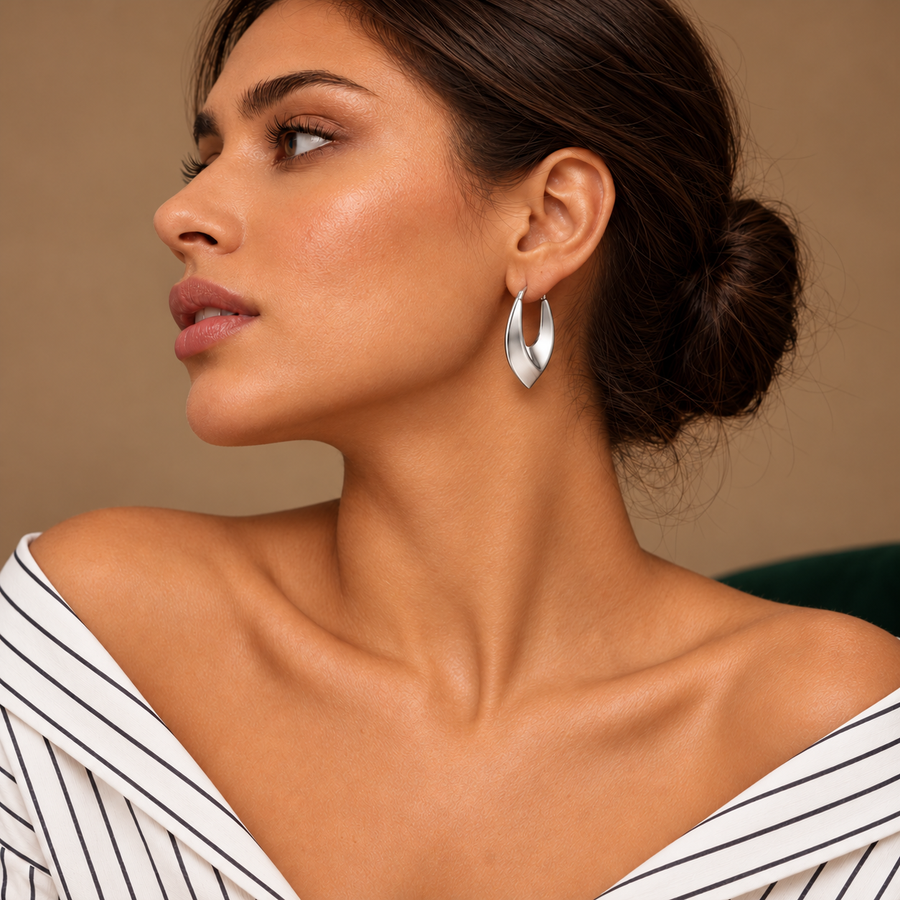 Vela Silver Sculptural Hoops worn by a model in an ivory striped shirt